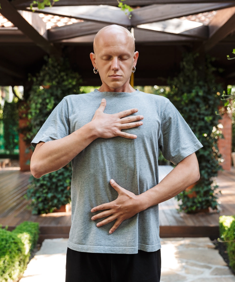 Ein Mann mit Glatze und auffälligen Ohrringen atmet tief durch bei geschlossenen Augen