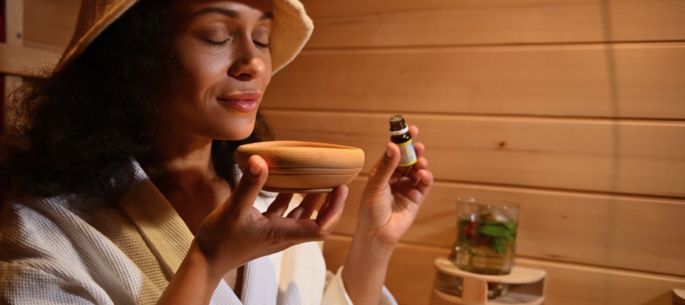 Eine Frau mit Saunahut genießt den Duft ätherischer Öle in einer Sauna