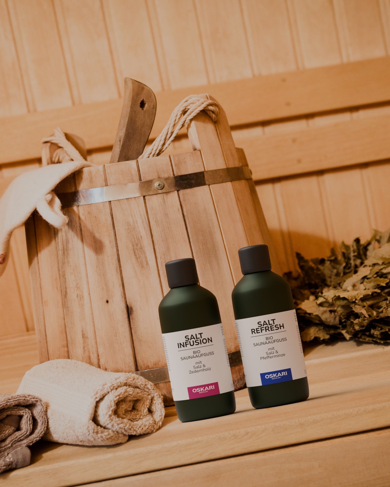 Oskari Bio Sauna Aufguss Set Edition Salt mit den beiden Saunaaufgüssen Salt Infusion und Salt Refresh in einer Sauna vor Saunaeimer