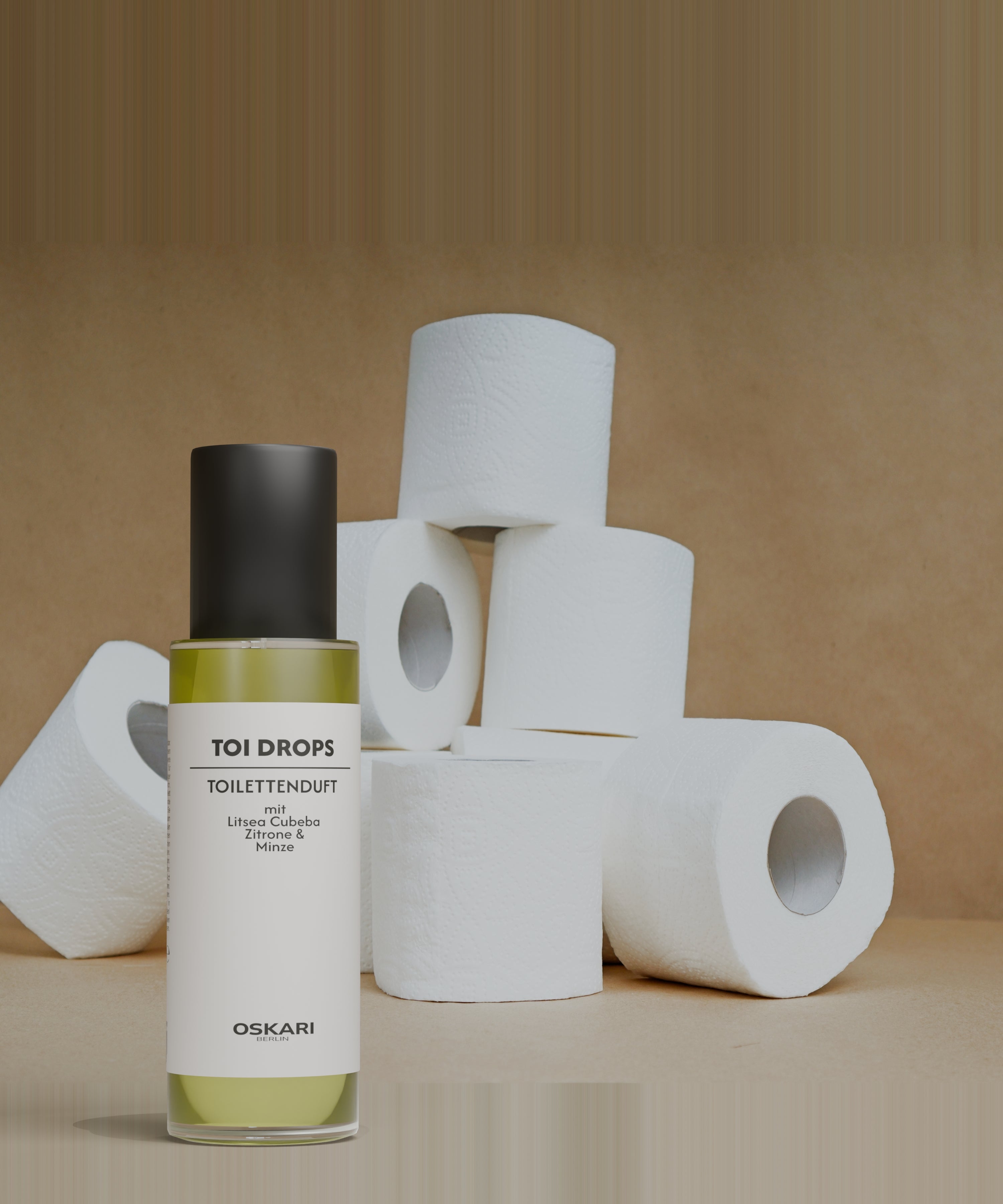 Toi Drops Toilettenduft vor einem Stapel Toilettenpapierrollen