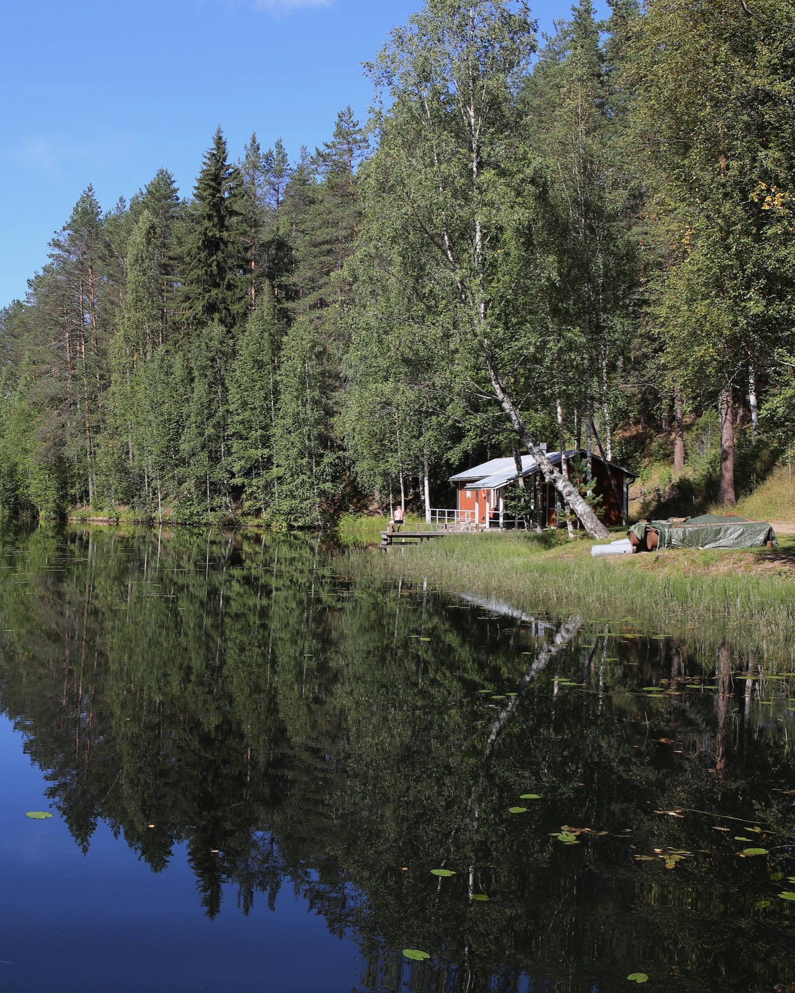 Eine rotgestrichene Holzhütte an einem ruhigen Waldsee in Finland