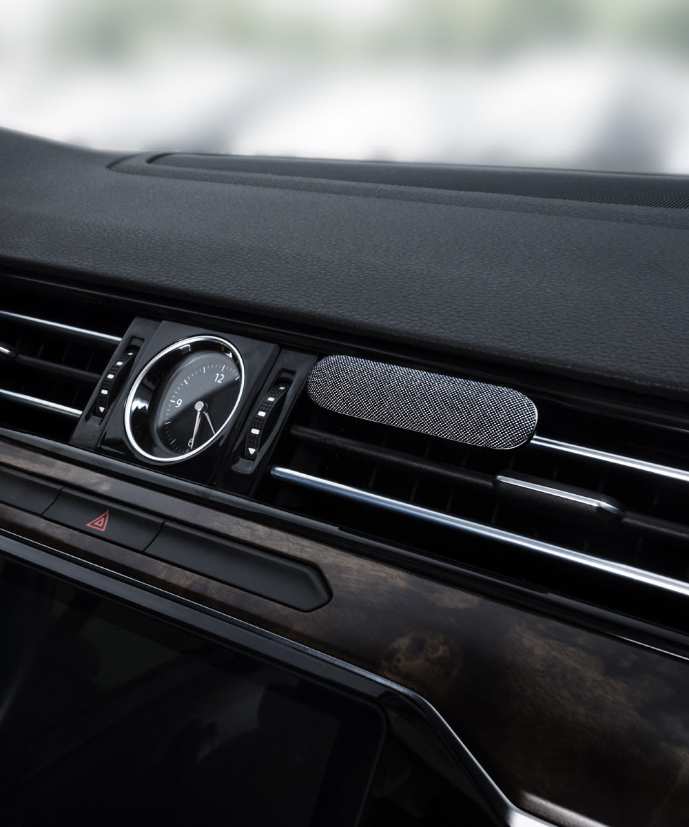 Auto Duft Diffuser mit grauem Stoff und aus Aluminium befestigt an einer Lüftungslamelle eines Autos