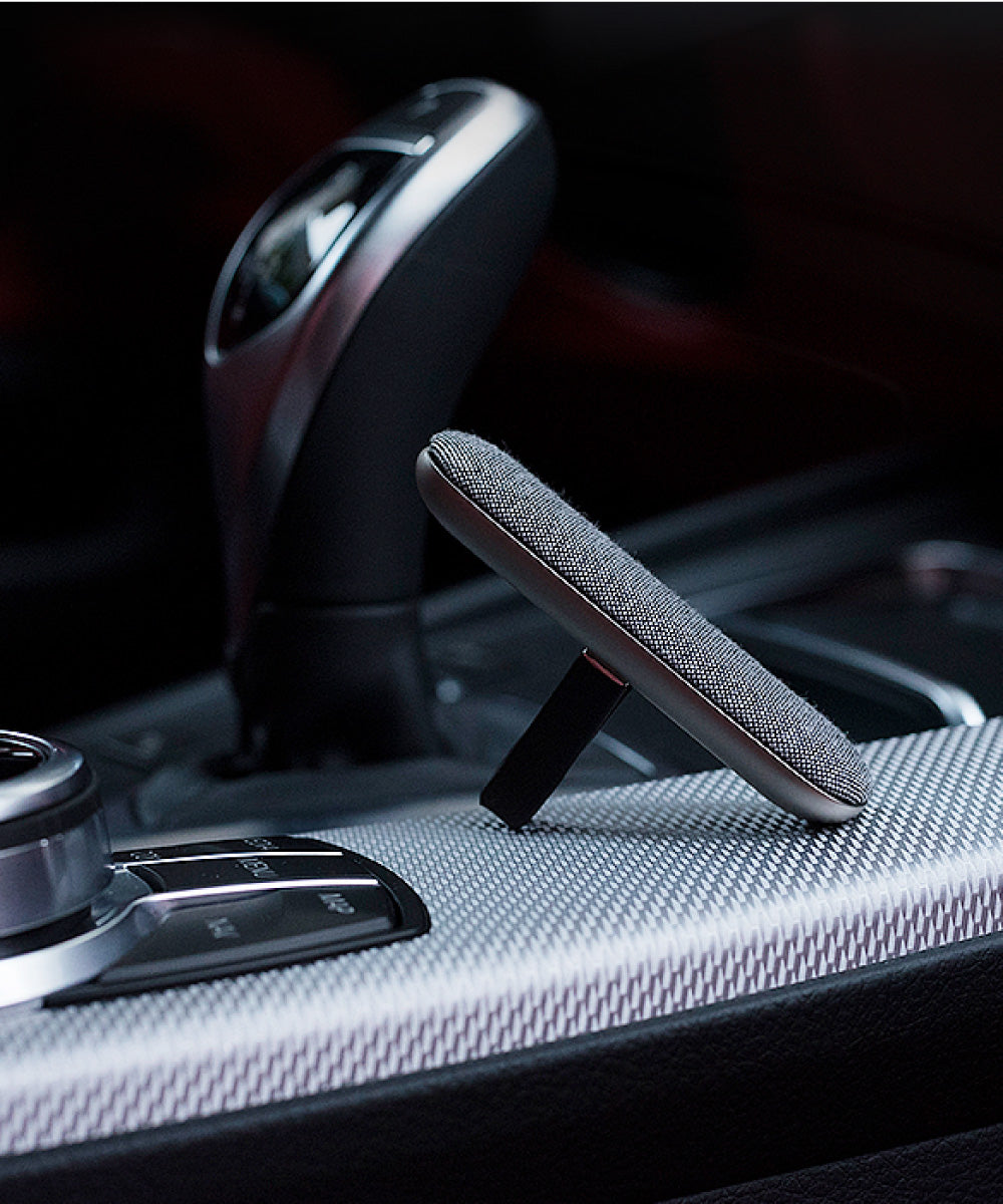 Oskari Lüftungsdiffuser für Autos lehnt am Schaltknauf eines teueren eleganten Autos