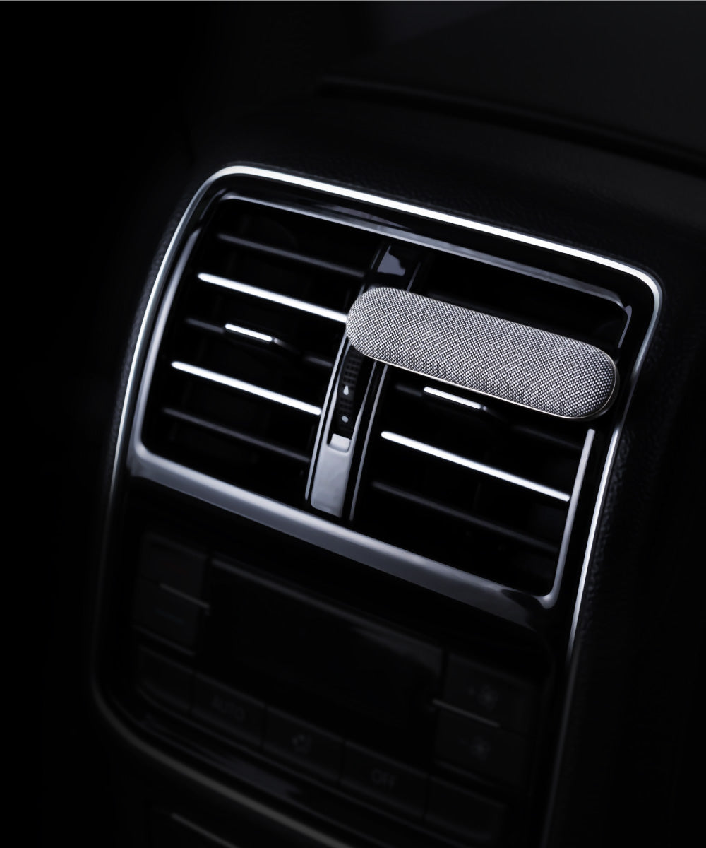 Der Oskari Autoduft Diffuser befestigt an einer schwarzen Autolüftung