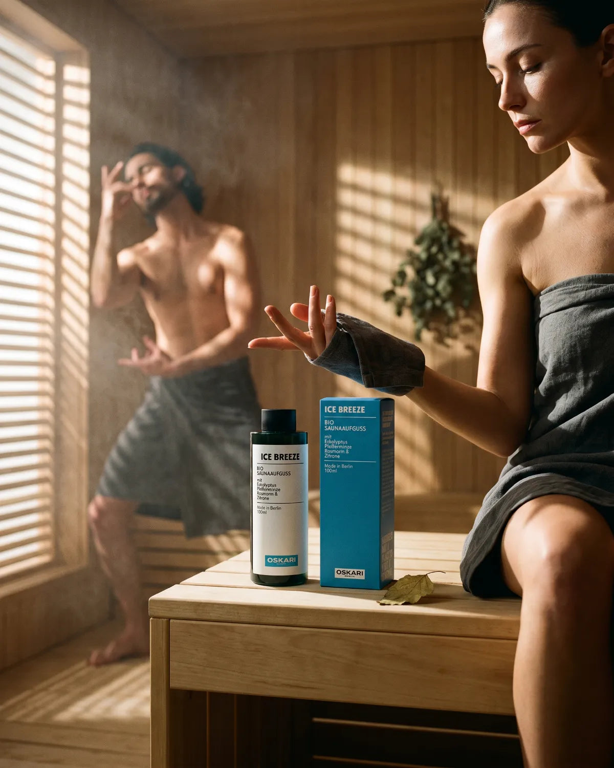 Eine junge Frau und ein junger Mann meditieren in einer Sauna mit dem Bio Saunaaufguss Ice Breeze von Oskari