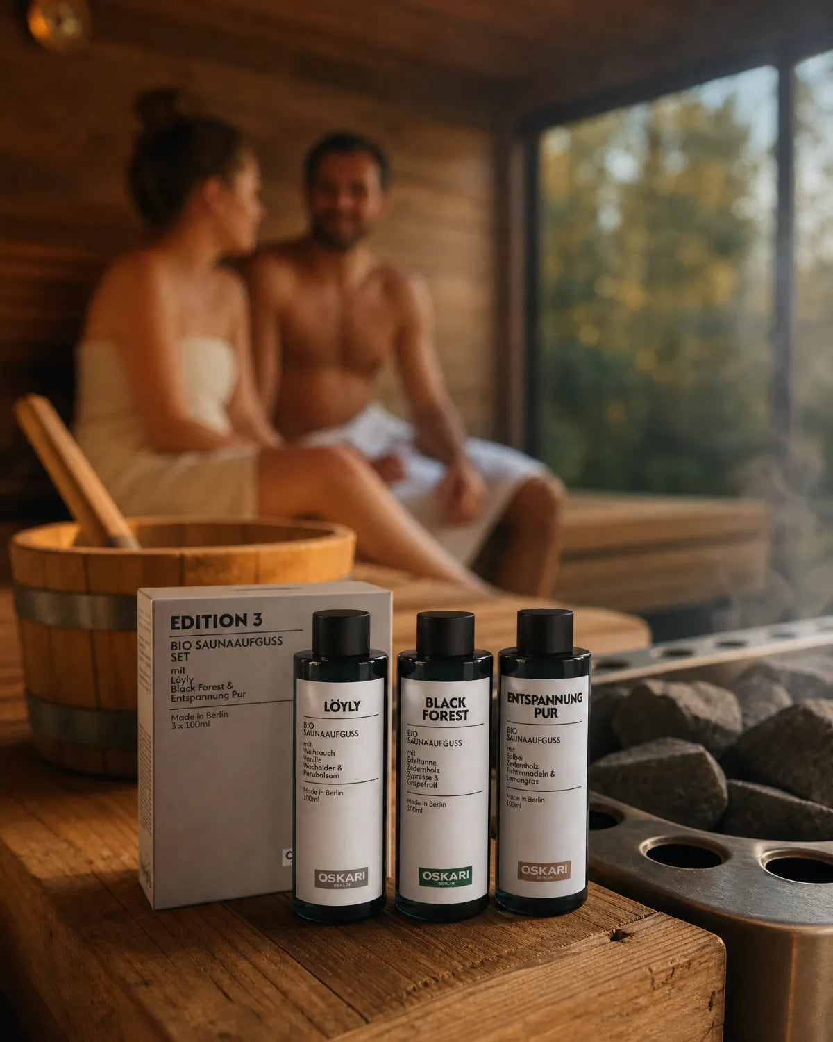 Bio Saunaaufgusset Edition 3 mit den Sorten Löyly, Black Forest und Entspannung Pur in der Sauna mi einem Paar im Hintergrund