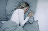 Junge Frau liegt im Bett und schläft tief und fest