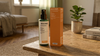 Das Oskari Bio Raumspray Kick Start mit Flasche und Schachtel auf einem hölzernen Couchtisch in einem modernen Wohnzimmer