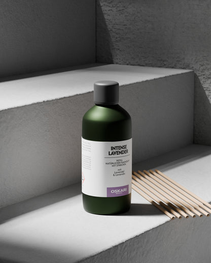 Auf einer Treppenstufe aus grauem Beton steht die Raumduft Nachfüllflasche Intense Lavender und die acht Duftstäbchen von Oskari 