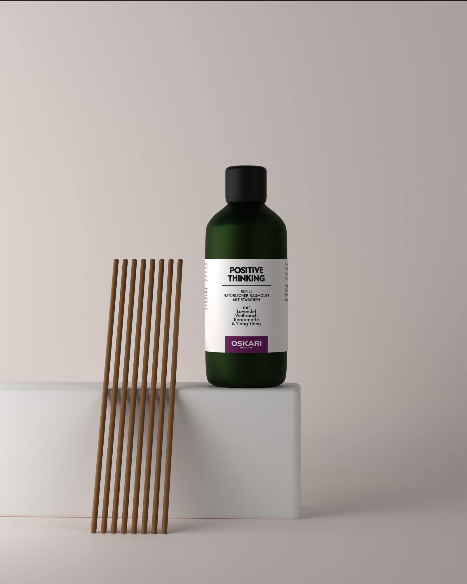Die grüne Glasflasche des Raumduft Nachfüllsets Positive Thinking neben den braunen Duftstäbchen aus Papier vor hellgrauem Hintergrund