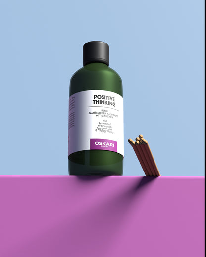 Das Oskari Raumduft Refill Set Positive Thinking auf einem lilafarbenen Podest vor blauem Hintergrund