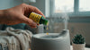 Eine weibliche Hand gibt einige Tropfen der Bio Duftmischung Sunshine in a Bottle von Oskari in einen modernen Ultraschallvernebler