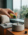 Eine weibliche Hand gibt einige Tropfen der Bio Duftmischung Sunshine in a Bottle von Oskari in einen modernen Ultraschallvernebler