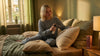 Junge Frau sitzt auf ihrem Bett in Nachtwäsche und benützt das Oskari Bio Kissenspray Bedtime Blend