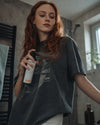 In einem Badezimmer bei Morgenlicht verwendet eine junge Frau das Bio Raumspray Kick Start von Oskari