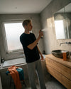 Ein versprüht das wachmachende Bio Raumspray Kick Start von Oskari in seinem Badezimmer im Morgenlicht