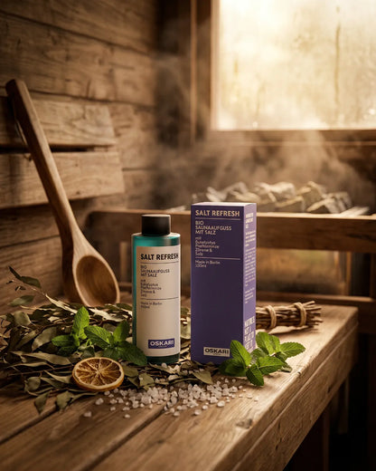 Oskari Bio Salzaufguss Salt Refresh mit Salz und Pflanzen in einer Holzsauna mit Dampf über dem Saunaofen